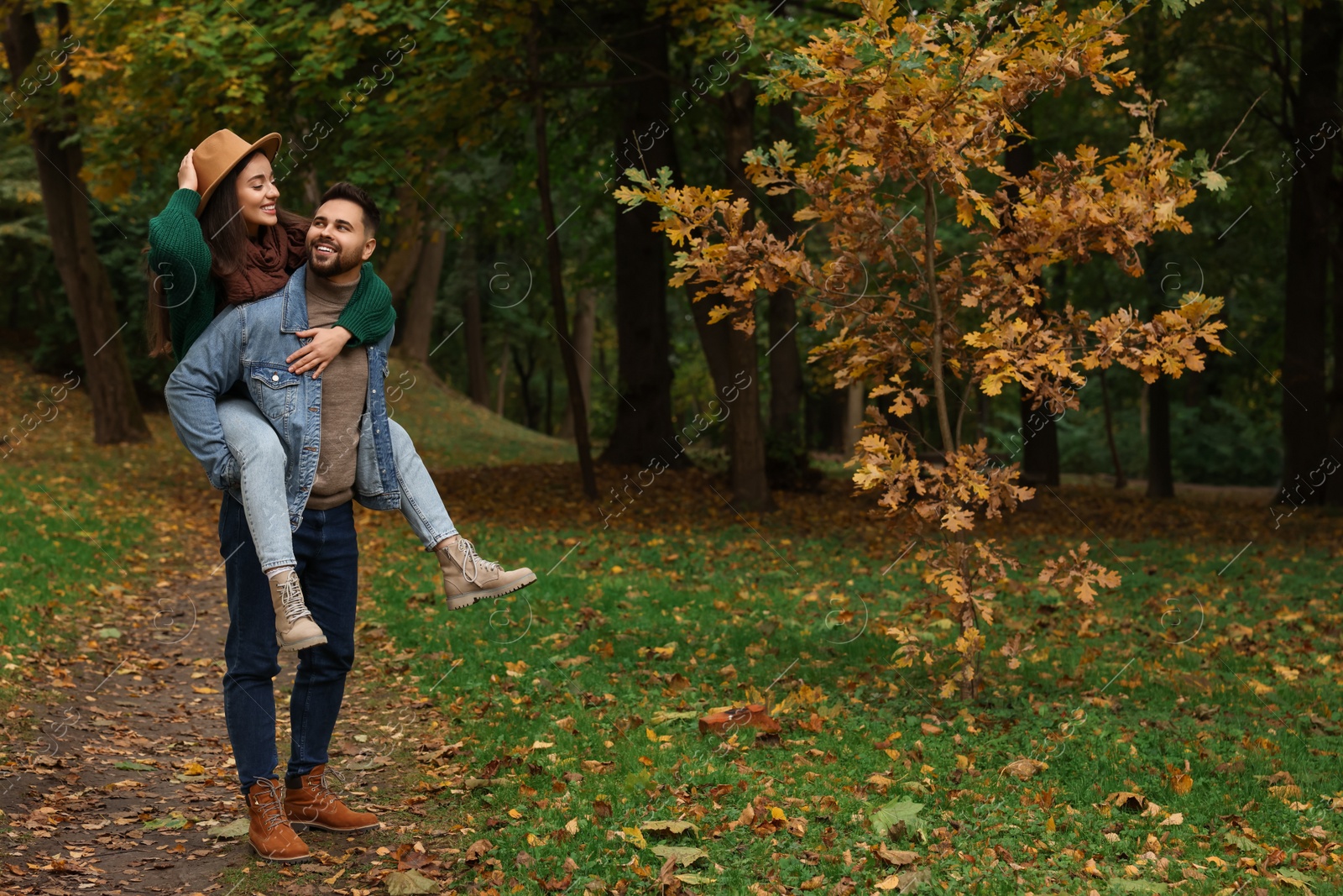 Photo of Romantic young couple spending time together in autumn park, space for text