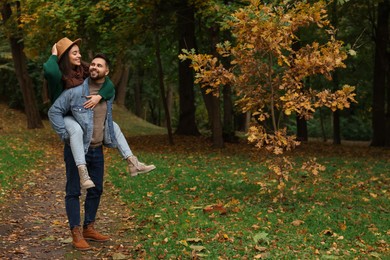 Romantic young couple spending time together in autumn park, space for text