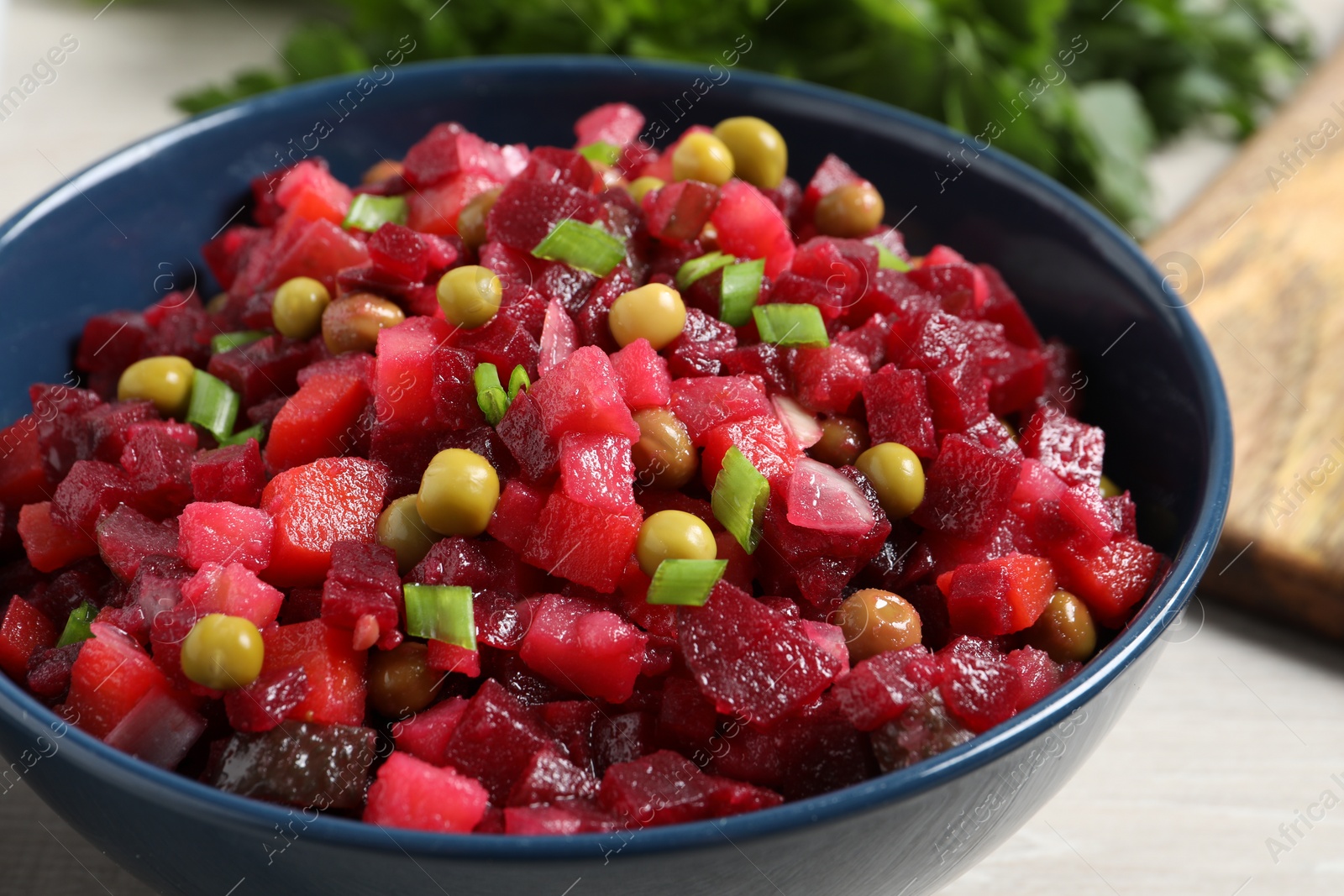 Photo of Bowl with delicious fresh vinaigrette salad on table, closeup