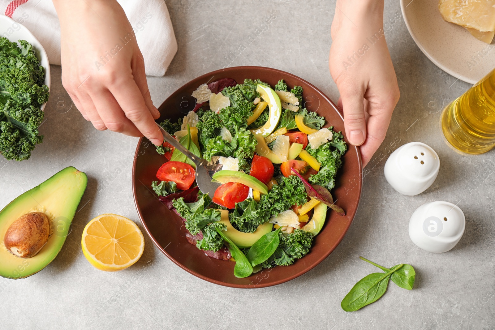 Photo of Woman cooking tasty kale salad on light grey table, top view