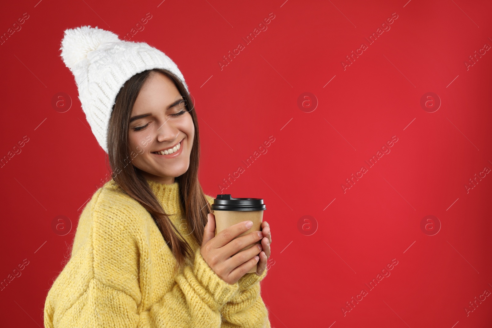 Photo of Happy beautiful woman with paper cup of mulled wine on red background. Space for text