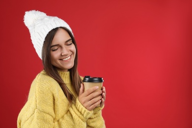 Photo of Happy beautiful woman with paper cup of mulled wine on red background. Space for text