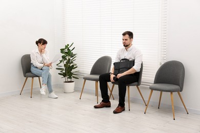 Photo of Man and woman waiting for job interview indoors