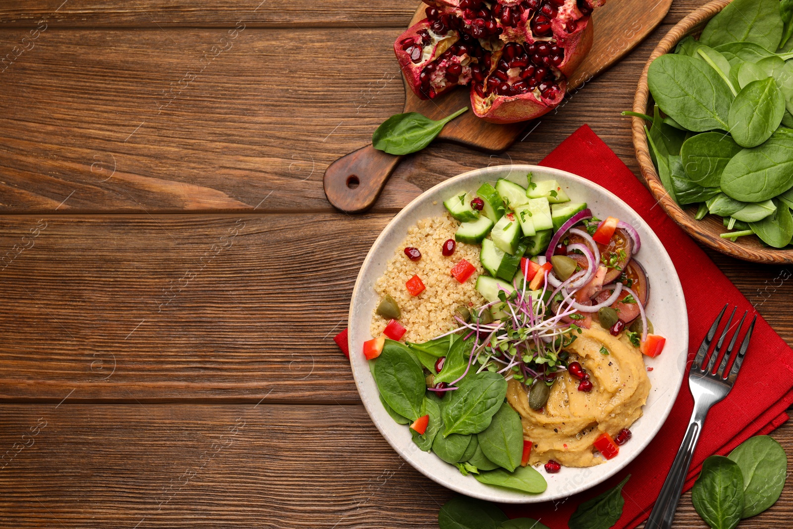 Photo of Delicious vegan bowl with cucumbers, spinach and bulgur on wooden table, flat lay. Space for text