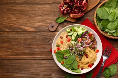 Delicious vegan bowl with cucumbers, spinach and bulgur on wooden table, flat lay. Space for text