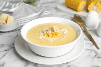 Photo of Delicious corn cream soup served on white marble table