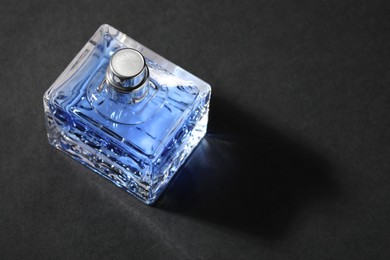 Photo of Blue men's perfume in bottle on black background, space for text