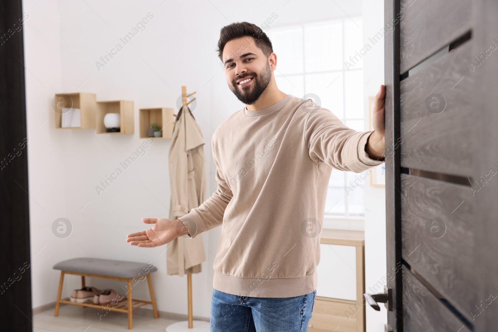 Photo of Happy man welcoming near door. Invitation to come indoors