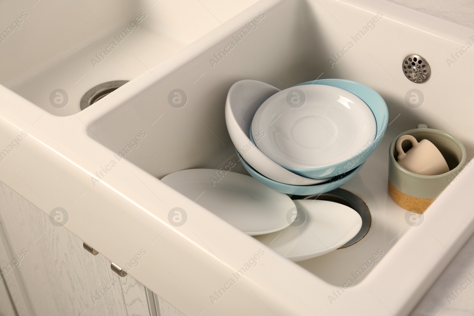 Photo of Clean tableware in white sink in kitchen