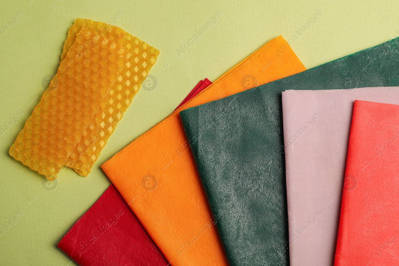 Photo of Different beeswax food wraps on light green background, flat lay