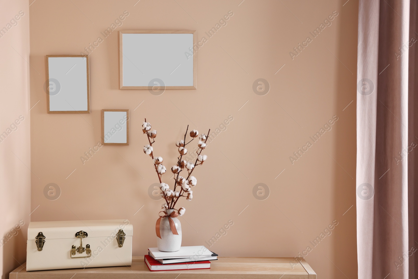 Photo of Vase with beautiful bouquet of white fluffy cotton flowers on wooden table in cozy room. Interior design