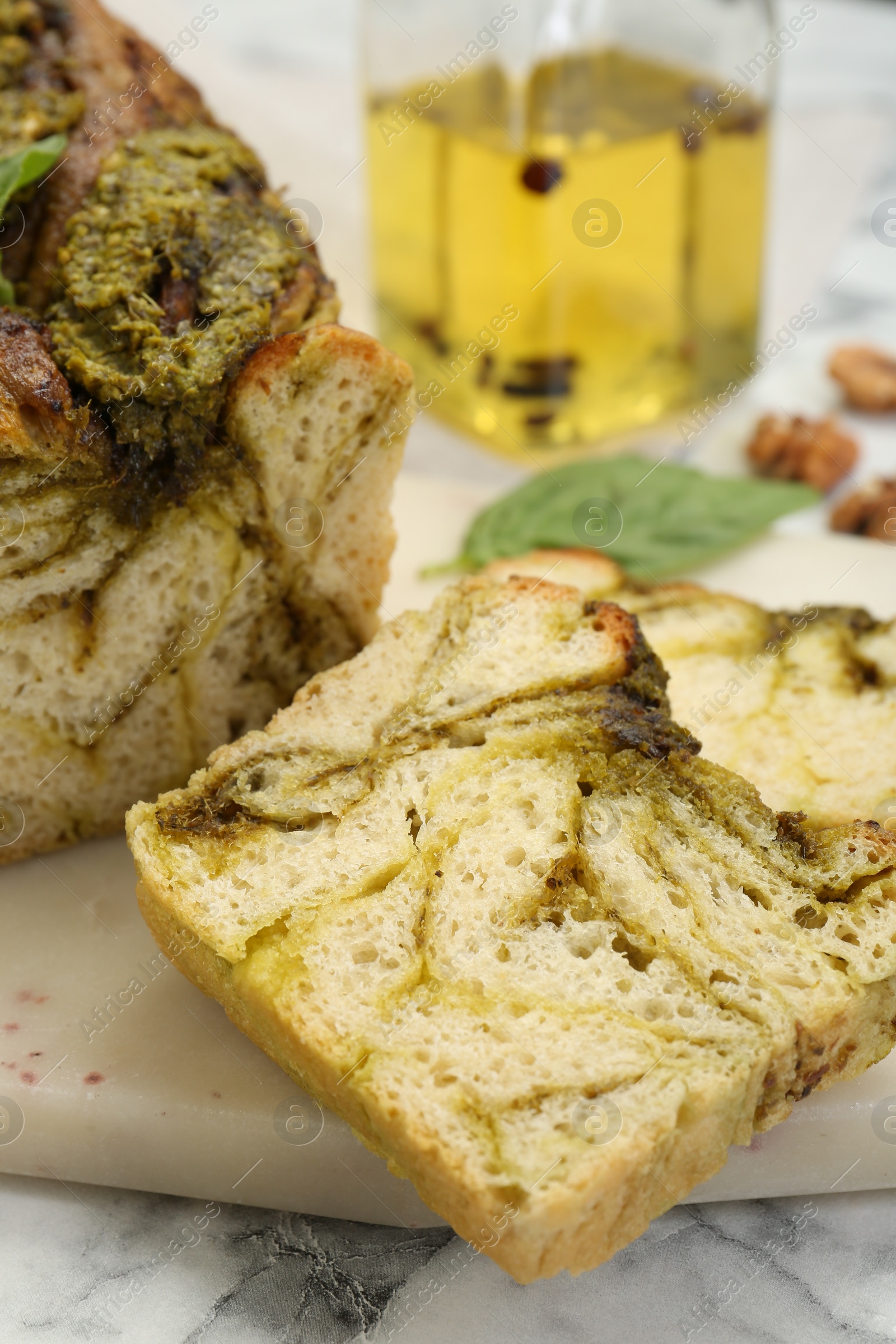 Photo of Freshly baked pesto bread on white marble table, closeup