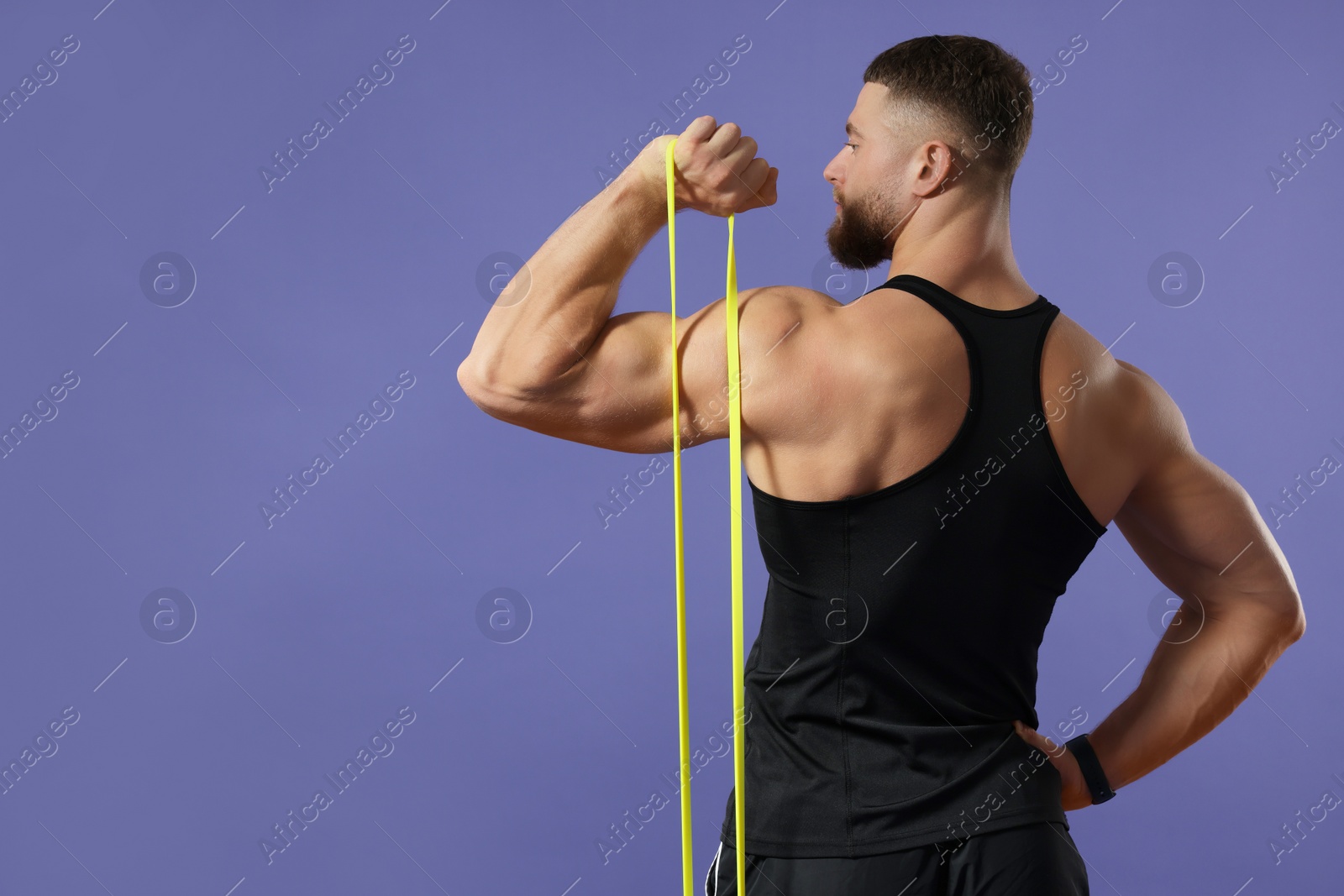 Photo of Muscular man exercising with elastic resistance band on purple background, back view. Space for text