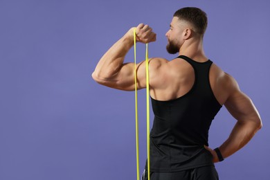Muscular man exercising with elastic resistance band on purple background, back view. Space for text