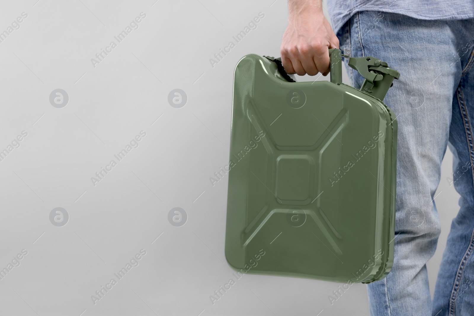 Photo of Man holding khaki metal canister on light grey background, closeup. Space for text