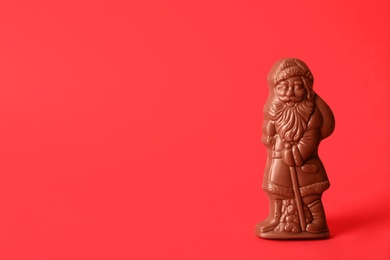 Photo of Sweet chocolate Santa Claus candy on red background, space for text