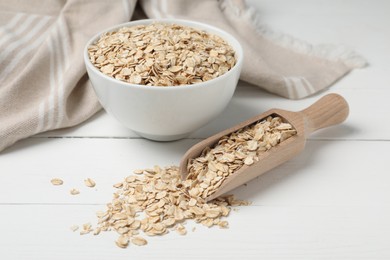 Photo of Bowl and scoop with oatmeal on white wooden table