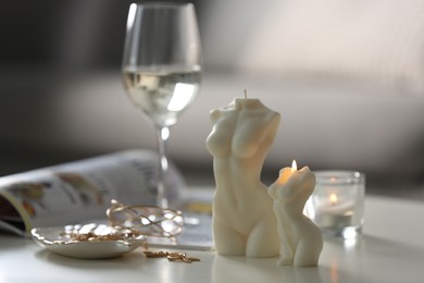 Beautiful body shaped candles and jewelry on white table indoors, space for text