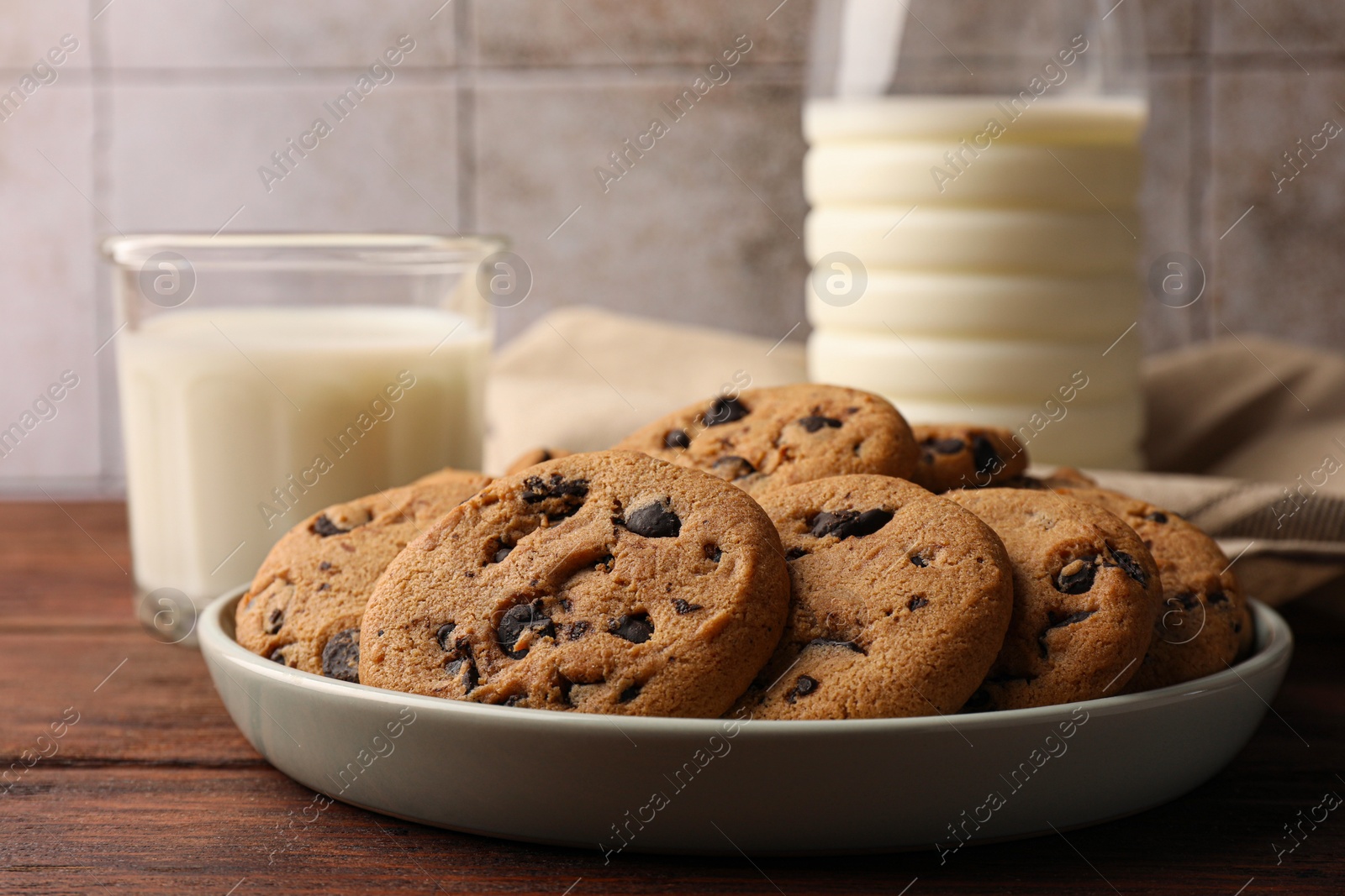 Photo of Delicious chocolate chip cookies and milk on wooden table, closeup