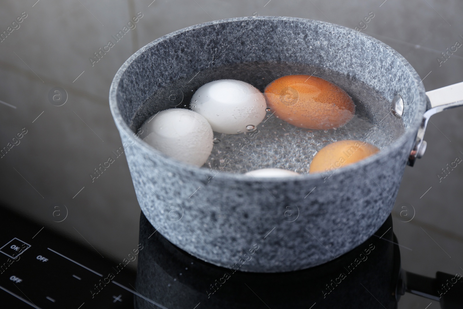 Photo of Chicken eggs boiling in saucepan on electric stove, closeup