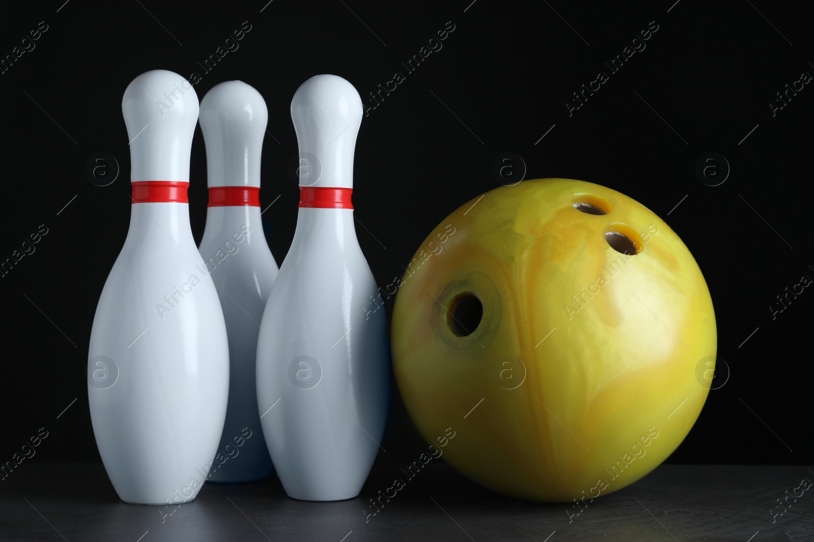 Photo of Yellow bowling ball and pins on black stone table