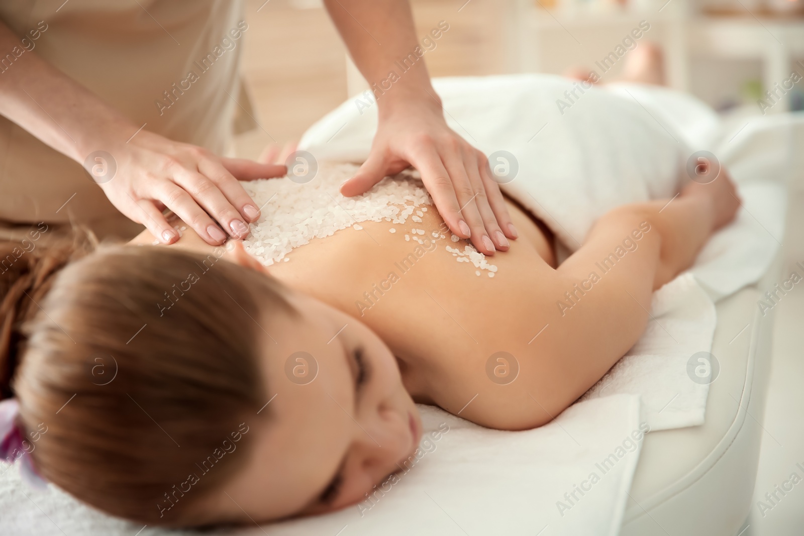 Photo of Beautiful young woman having massage with body scrub in spa salon