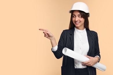 Photo of Architect in hard hat with draft pointing at something on beige background, space for text
