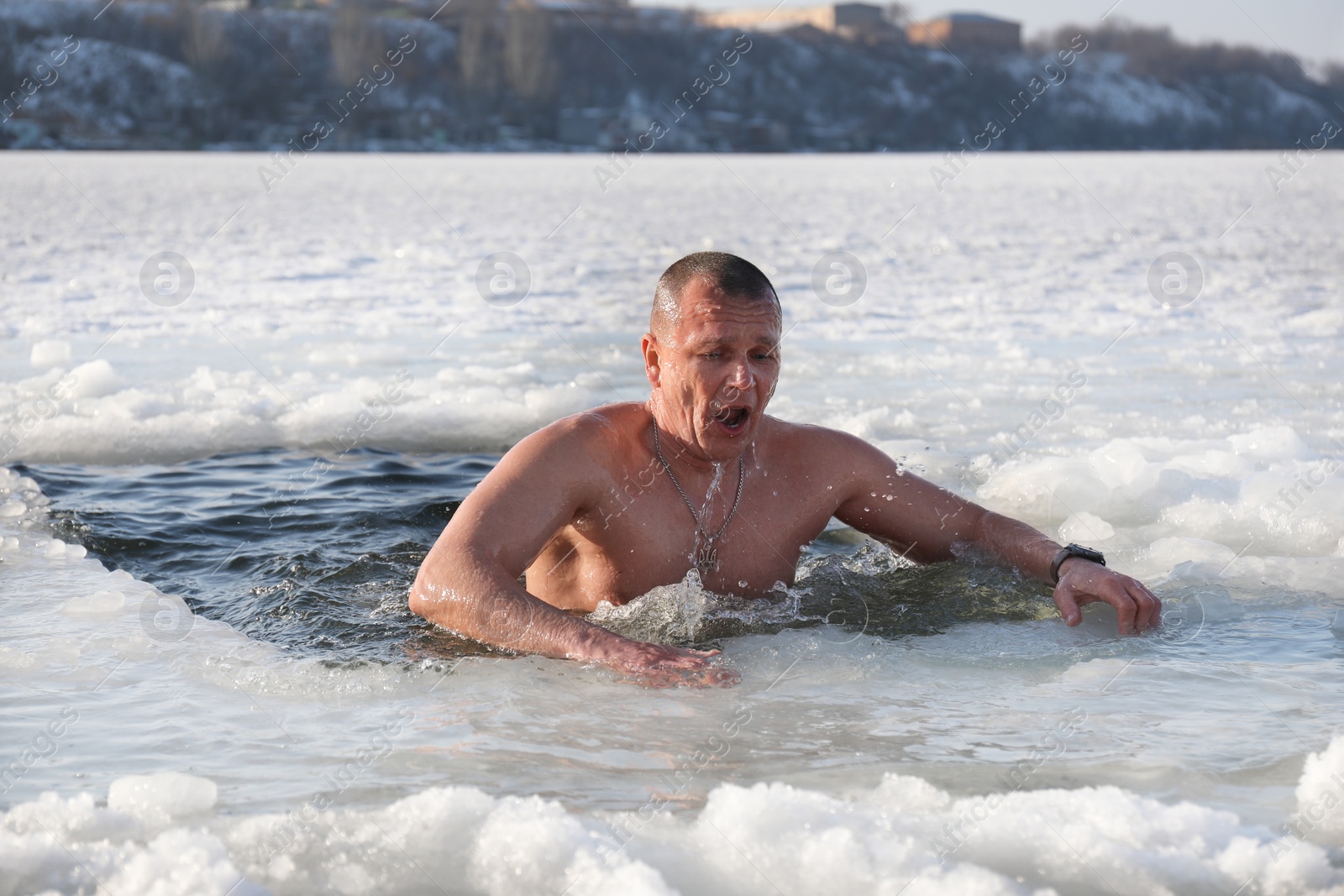 Photo of MYKOLAIV, UKRAINE - JANUARY 06, 2021: Man immersing in icy water on winter day