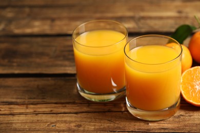 Glasses of fresh tangerine juice and fruits on wooden table