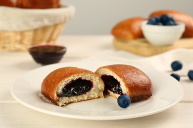 Delicious baked patty with jam and blueberries on white wooden table