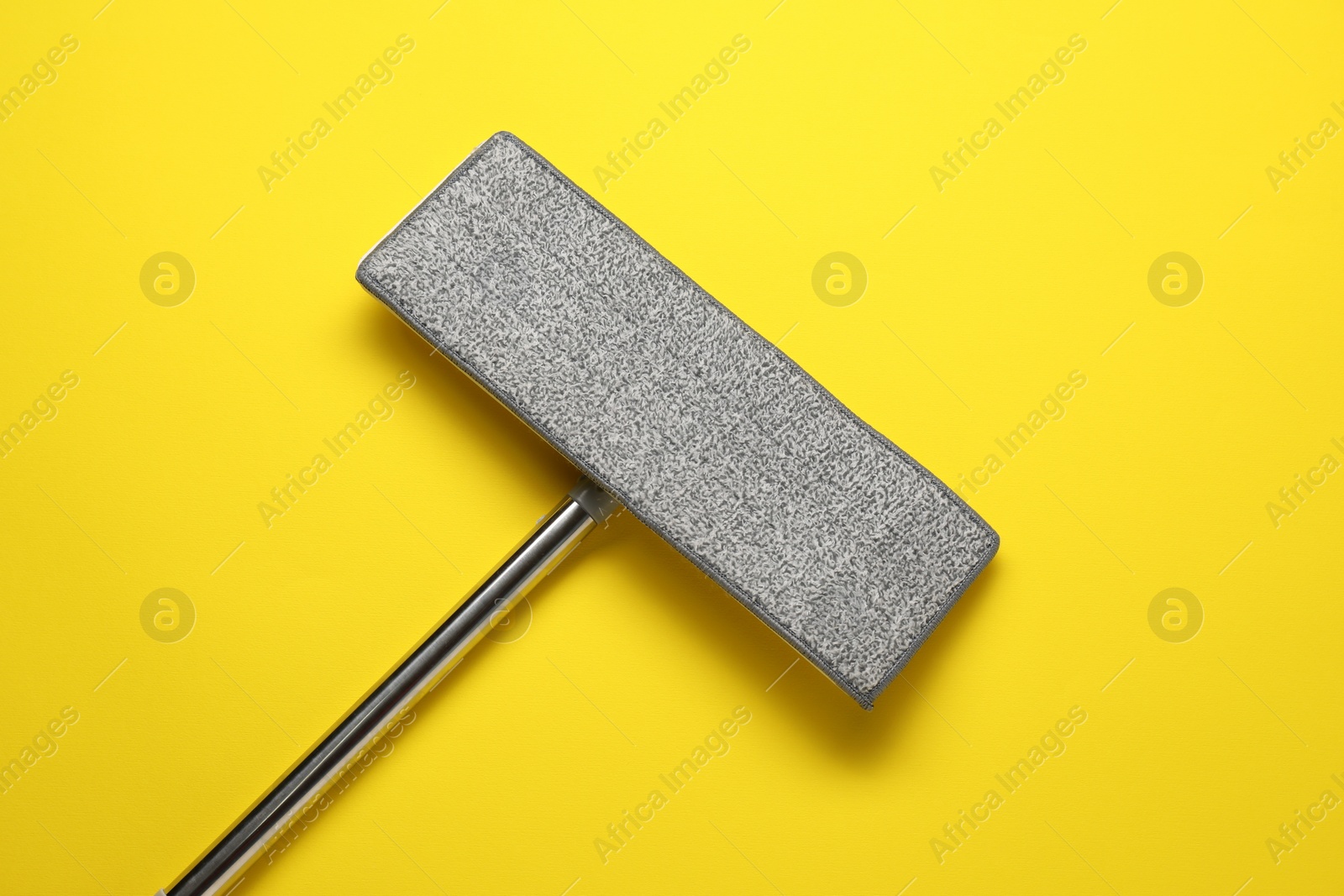 Photo of Mop with metal handle on yellow background, top view