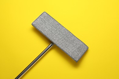 Mop with metal handle on yellow background, top view