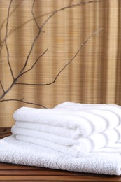 Stacked soft towels on wooden table and tree branches indoors