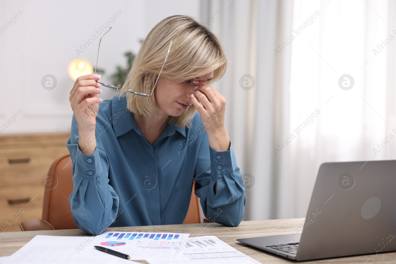 Photo of Overwhelmed woman with glasses sitting at table in office