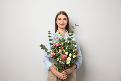 Photo of Florist with beautiful bouquet on light background