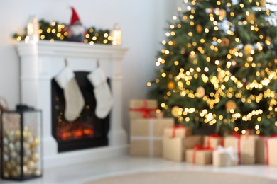 Blurred view of many different gift boxes under Christmas tree and festive decor in living room