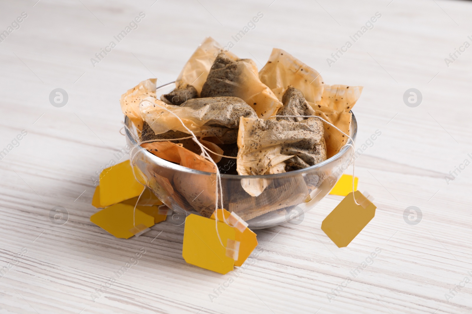 Photo of Bowl with used tea bags on white wooden table