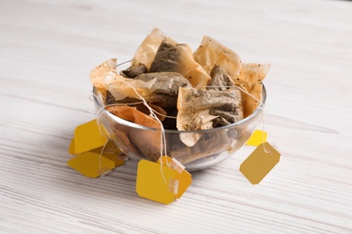 Photo of Bowl with used tea bags on white wooden table