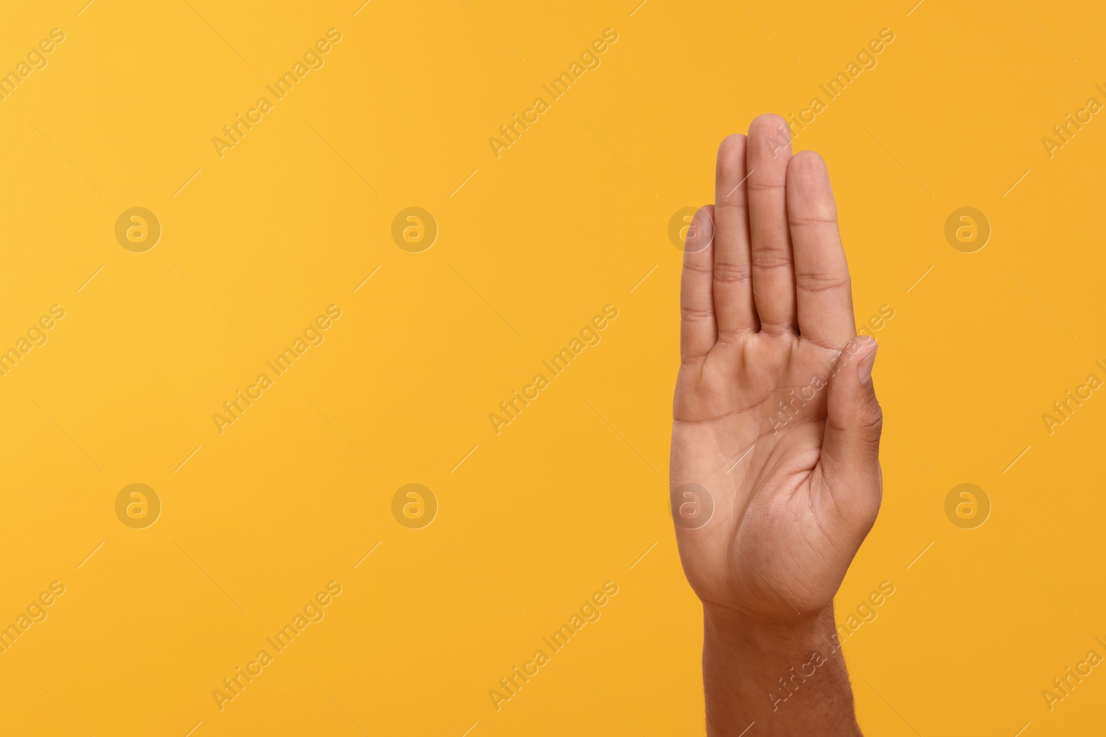 Photo of Man giving high five on yellow background, closeup of hand. Space for text