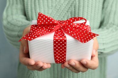 Woman holding beautiful Christmas gift with bow, closeup