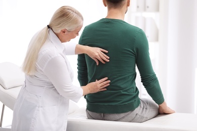 Photo of Chiropractor examining patient with back pain in clinic