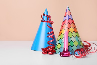 Colorful party hats, streamers and blower on white table, space for text. Birthday celebration