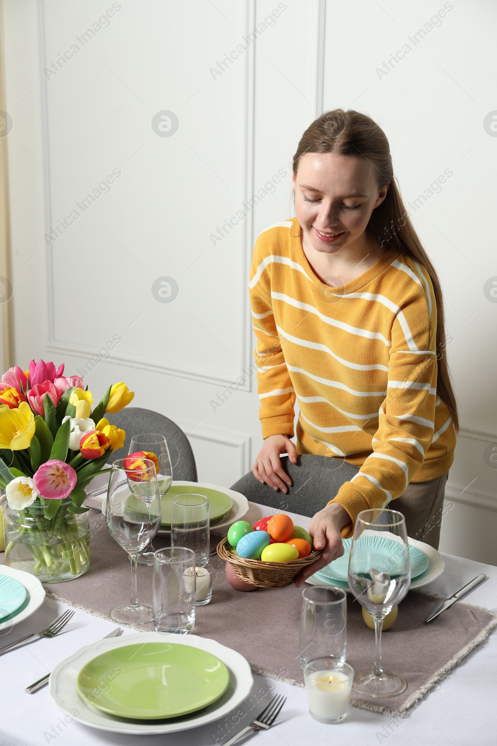 Photo of Woman setting table for festive Easter dinner at home