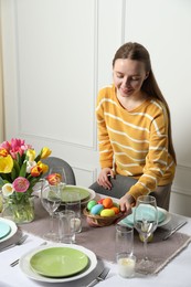 Photo of Woman setting table for festive Easter dinner at home