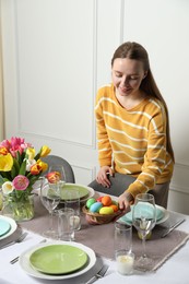 Woman setting table for festive Easter dinner at home