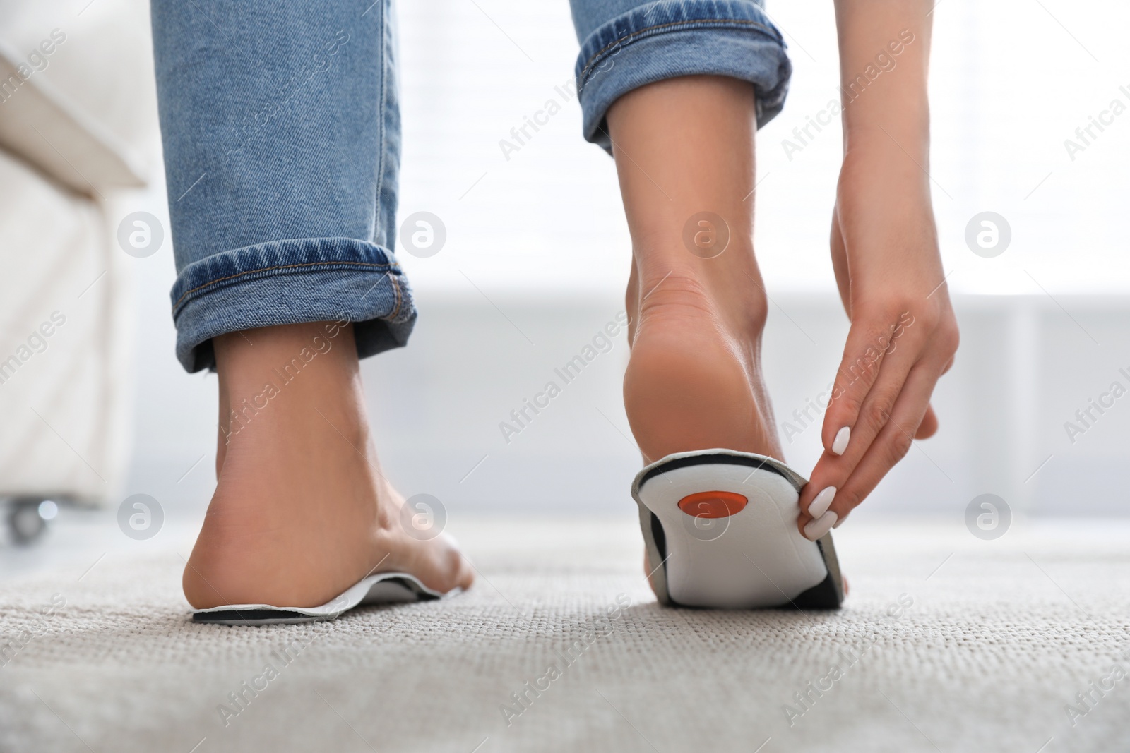 Photo of Woman fitting orthopedic insole at home, closeup