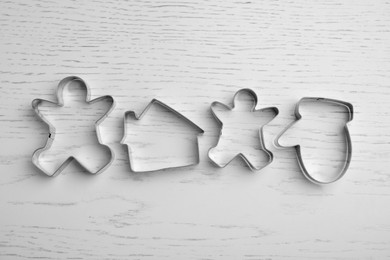 Different cookie cutters on white wooden table, flat lay