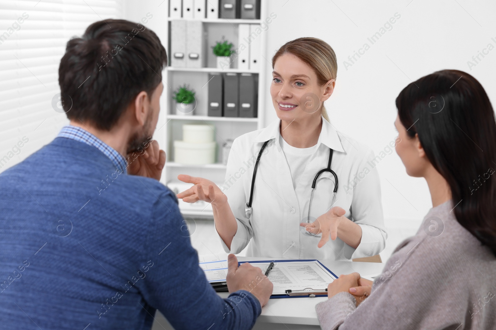 Photo of Couple having appointment with fertility doctor in clinic. Patient consultation