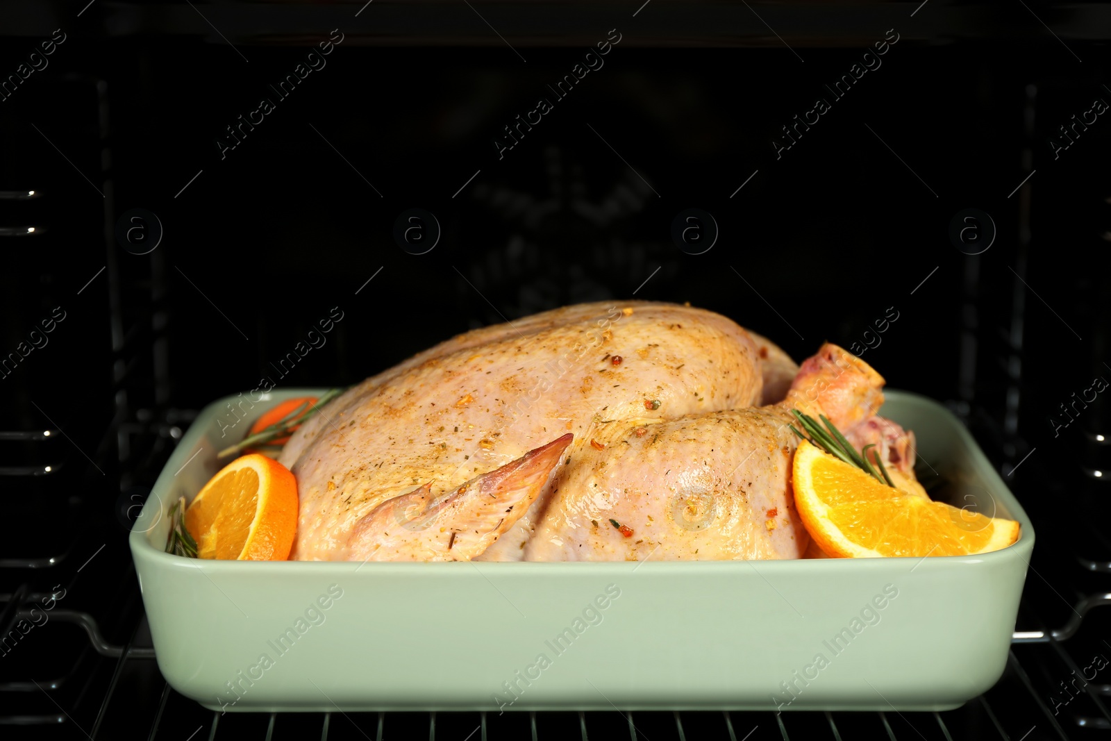 Photo of Pan with chicken and oranges in oven