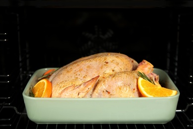 Photo of Pan with chicken and oranges in oven